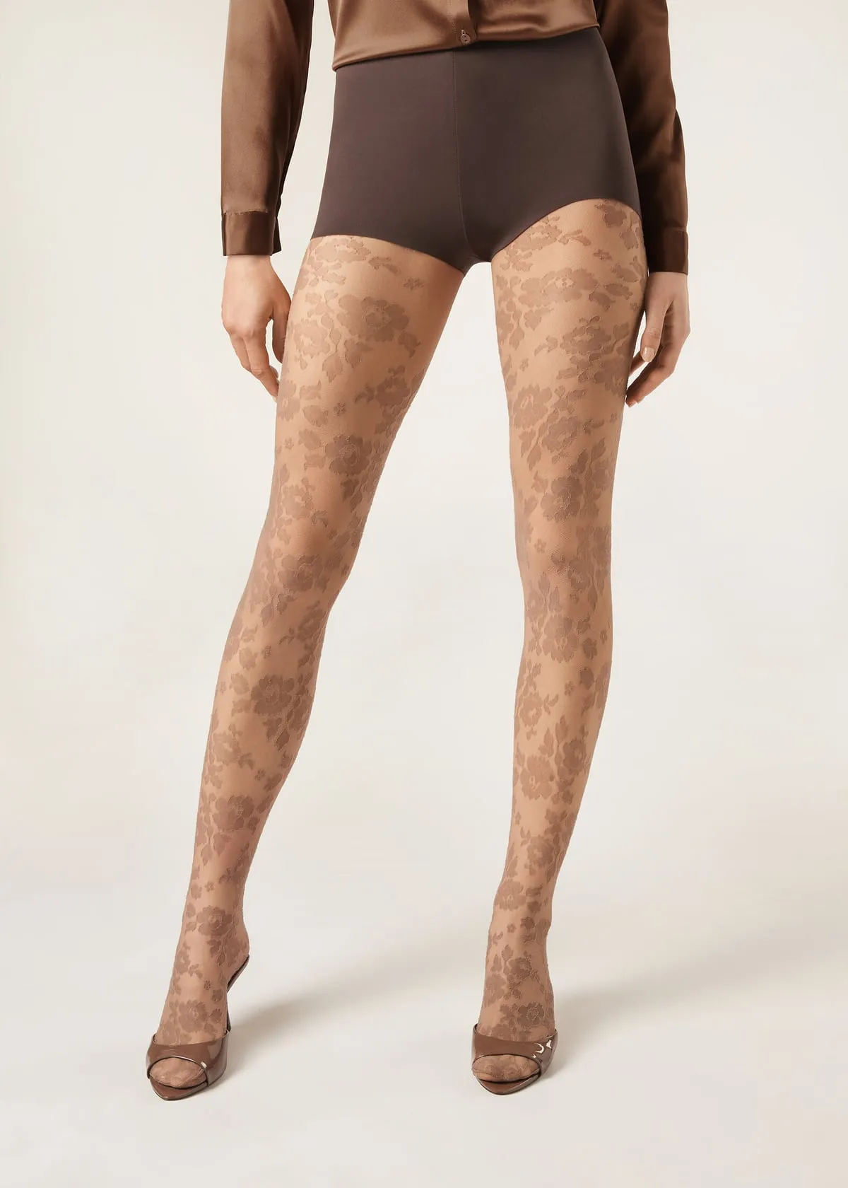 Calzedonia Floral Sheer Tights in a nude-brown shade, 40 denier tulle with an all-over floral pattern, worn with brown shorts and patent sandals