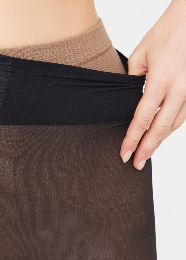 Collant termico effetto velato Calzedonia: una mano abbassa in vita lo strato esterno nero velato e mostra sotto lo strato termico color carne