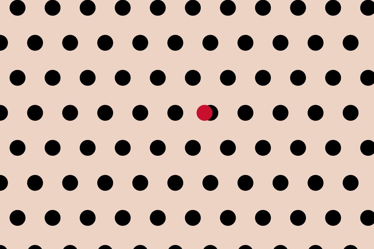 Black polka dots on a nude background, with one red dot