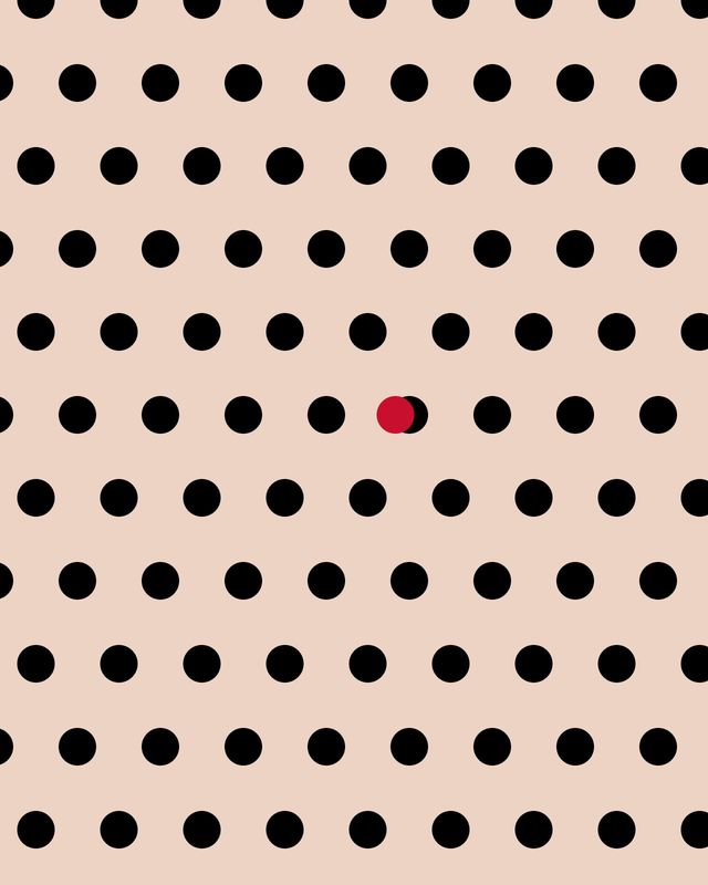 Black polka dots on a nude background, with one red dot