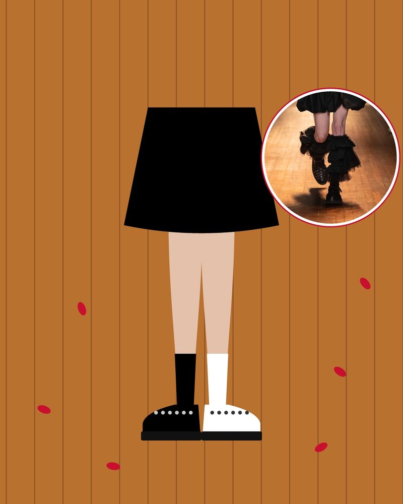 Illustration: a black sock with a black studded shoe and a white sock with a white studded shoe under a black skirt, on a parquet floor with red petals, with a photo of the runway look