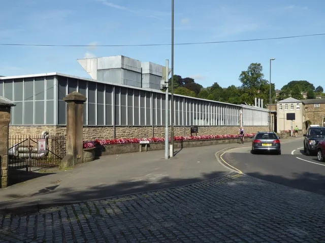 The Courtaulds plant in Belper, a long low glazed building by a road, with red flowers along the wall