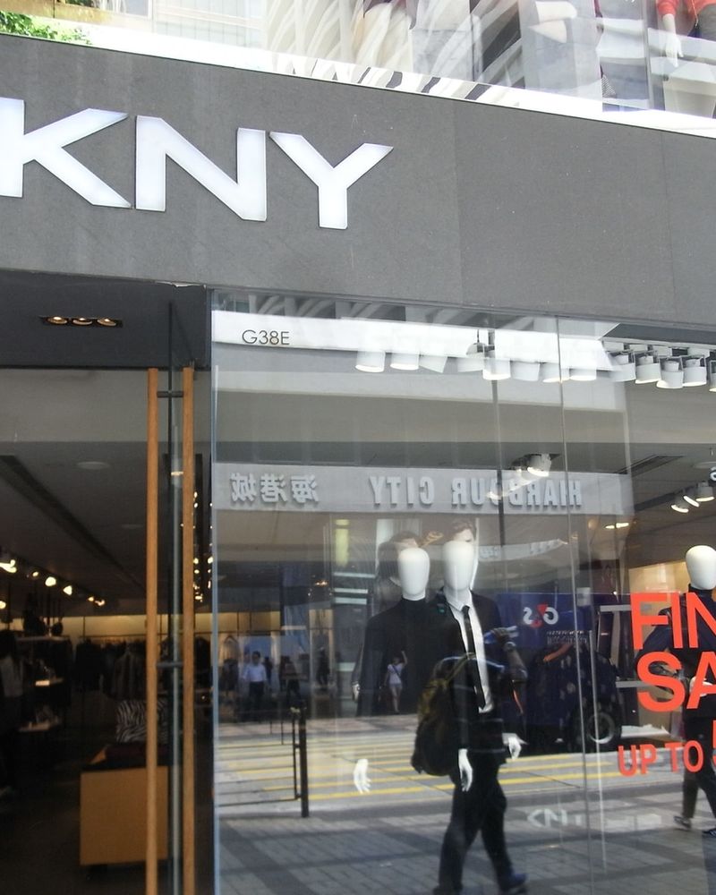 The white DKNY sign on the grey facade of a store on Canton Road, Hong Kong, with the entrance and the window